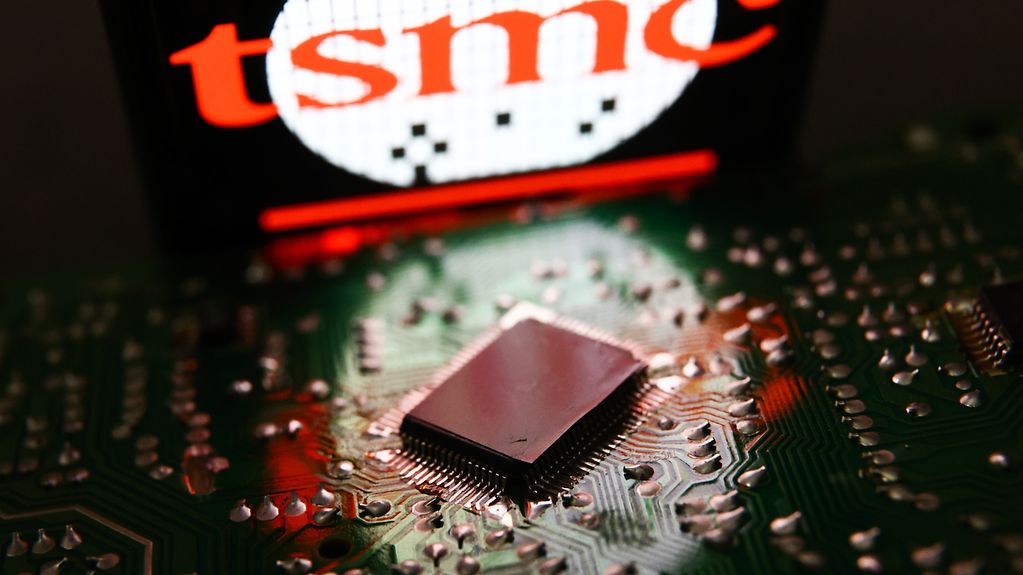 Das Foto zeigt das Logo von TSMC im Hintergrund mit einem Chip im Vordergrund